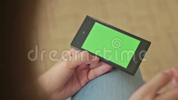 漂亮的女人拿着绿色屏幕显示和触摸的智能手机视频的预览图