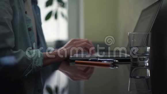 一杯水铅笔记事本和粘在桌子上商业人士使用笔记本电脑视频的预览图