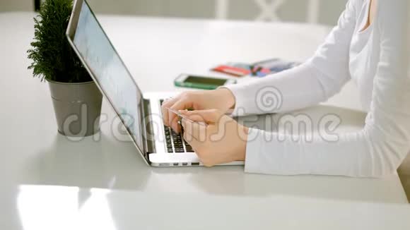 一位年轻女子在网上商店买东西并通过手机支付信用卡视频的预览图
