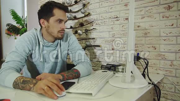 年轻的胡子商人穿着灰色运动衫在明亮的办公室工作视频的预览图
