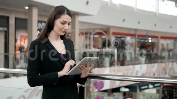 微笑着成熟的职业女商人在办公室手持数码平板电脑机场或购物场所的黑发女人视频的预览图