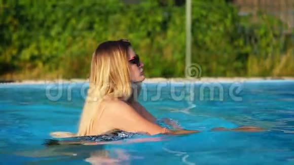 戴太阳镜的女孩在度假胜地的游泳池游泳视频的预览图