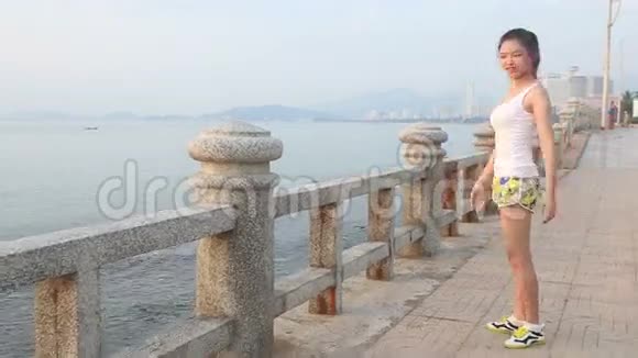 1亚洲女孩黎明时分在城市的堤岸上做运动视频的预览图