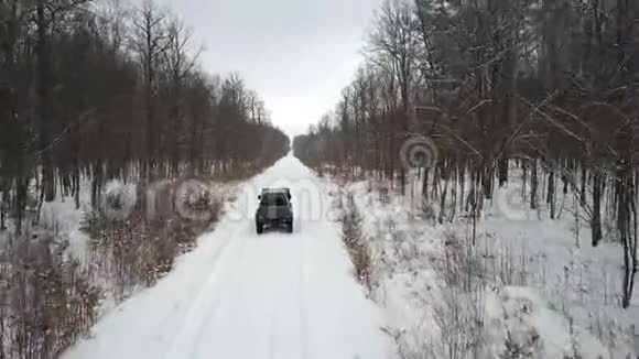 越野车6x6在雪地森林的冬季道路上行驶后景视频的预览图