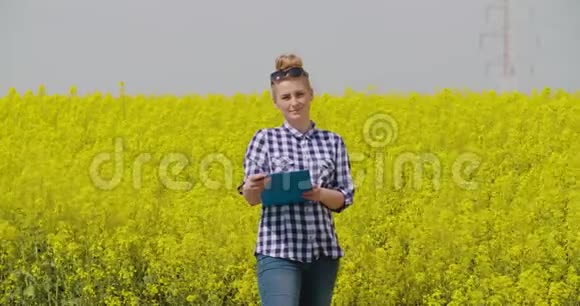 油菜田剪贴板上自信的女农民写作视频的预览图