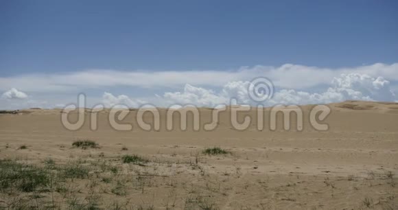 巨大的白色蓬松云团在沙漠沙丘上翻滚视频的预览图