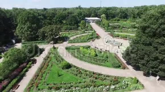 四架直升机拍摄美丽的绿色夏季花园与花坛和喷泉在中心晴天视频的预览图