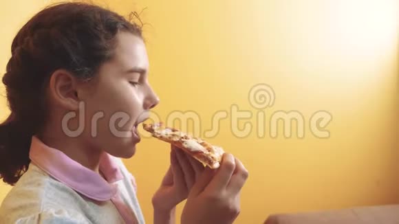 快乐的小女孩吃一片披萨的概念十几岁的孩子饿了吃一片比萨饼的生活方式慢动作视频的预览图