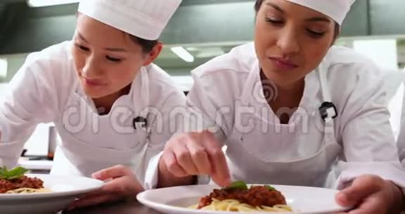 一排厨师用罗勒叶装饰意大利面菜肴视频的预览图