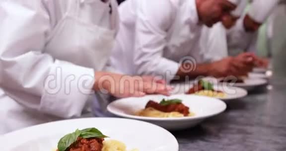 厨师团队用罗勒叶装饰意大利面菜肴视频的预览图