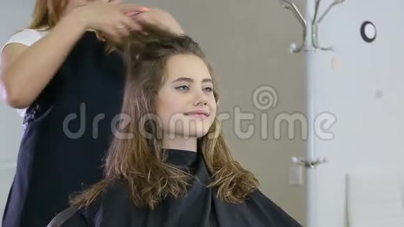 专业的理发师为少女准备发型用理发器修头发视频的预览图