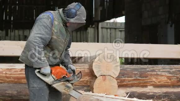 建筑工人为未来的家砍柴电锯建筑工人头上戴防护面罩和耳机视频的预览图