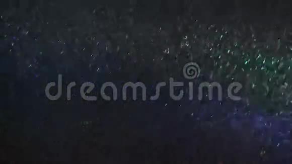 白色的雪落在夜晚在绿色和蓝色的光束中视频的预览图