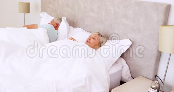 一对安静的夫妇睡在床上女人关掉了闹钟视频的预览图