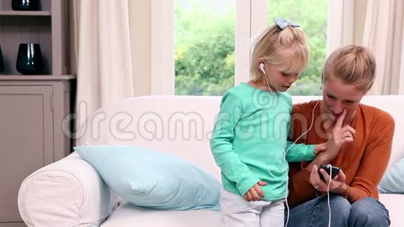 可爱的小女孩和妈妈一起听音乐视频的预览图