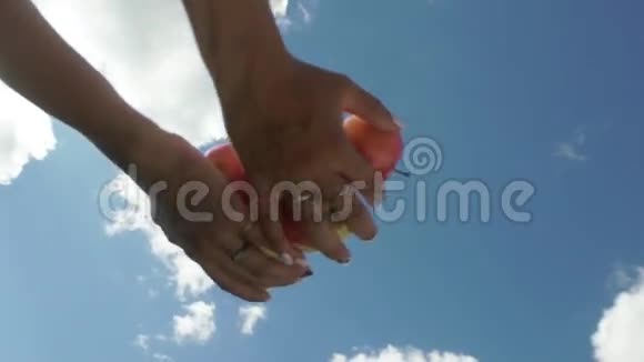 雌性手在蓝天的背景上扔苹果慢动作视频的预览图
