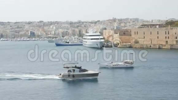 船游艇在马耳他瓦莱塔市的背景下航行宽镜头背景中新建房屋视频的预览图