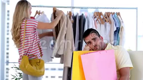 无聊的男人而他的女朋友在购物视频的预览图