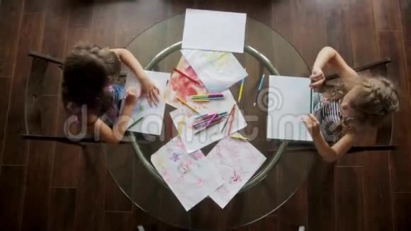 两个小女孩坐在桌子旁用蜡笔画画顶部视图视频的预览图
