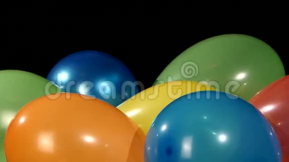 很多五颜六色的气球旋转在黑色上视频的预览图