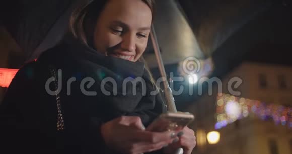 年轻女子晚上在城市里使用智能手机视频的预览图