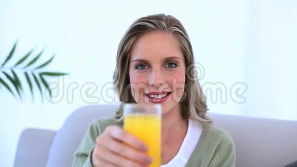 女人坐在沙发上展示她的一杯橙汁视频的预览图