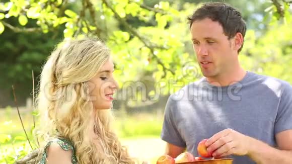 快乐的一对夫妇在花园里一起吃苹果视频的预览图