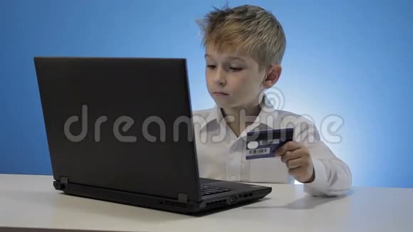 可爱的小男孩使用笔记本电脑和信用卡视频的预览图