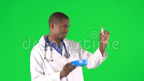 一名少数民族男性医生用钳子检查药片的照片视频的预览图