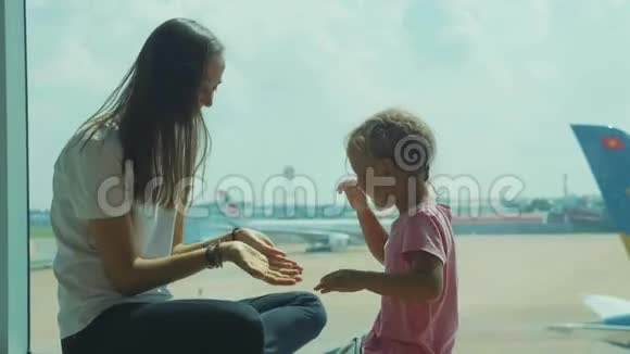 可爱的妈妈和可爱的小女儿在机场玩视频的预览图