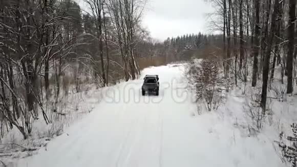 越野车6x6在雪地森林的冬季道路上行驶后景视频的预览图