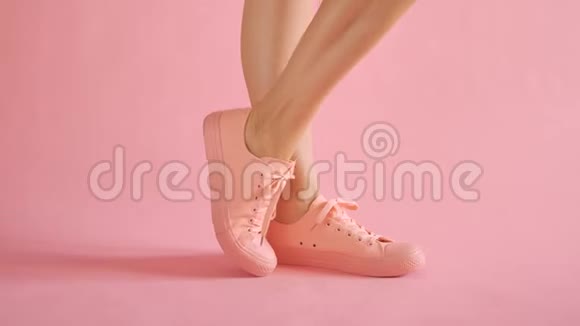 在珊瑚色背景下穿着运动鞋跳舞的苗条女性腿视频的预览图