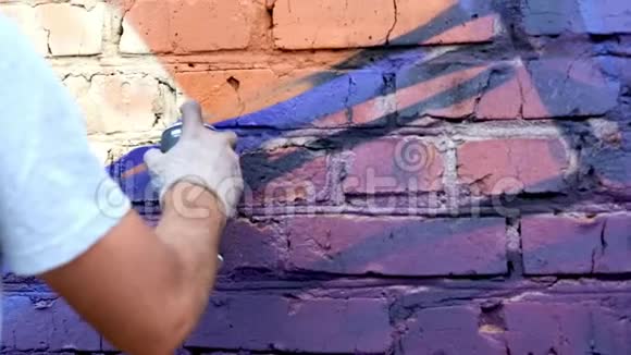 一个带着一罐油漆的年轻人在墙上涂鸦一手特写视频的预览图