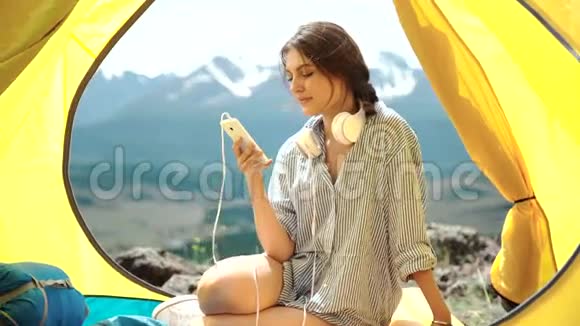 在帐篷里听mp3播放器的年轻女子视频的预览图