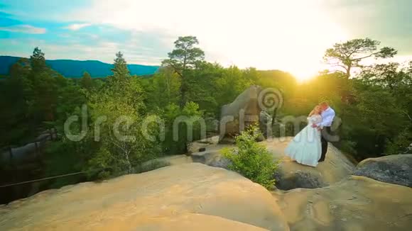 一对夫妇爬上岩石欣赏日出日落视频的预览图