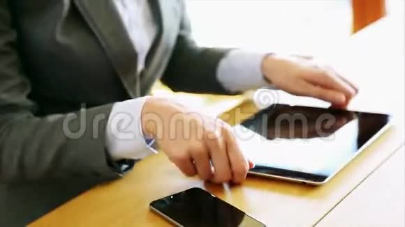 女商人在办公桌上使用平板电脑和智能手机视频的预览图