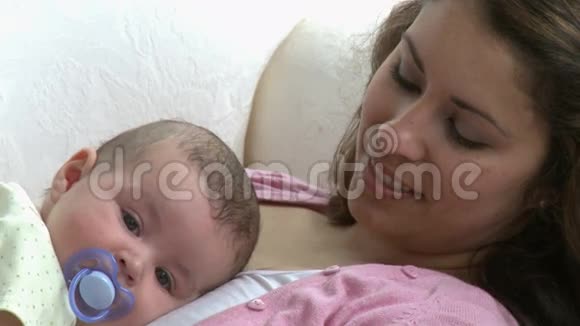 漂亮的年轻妈妈和她的孩子躺在沙发上视频的预览图