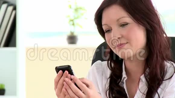 快乐的女人坐在扶手椅上发短信视频的预览图