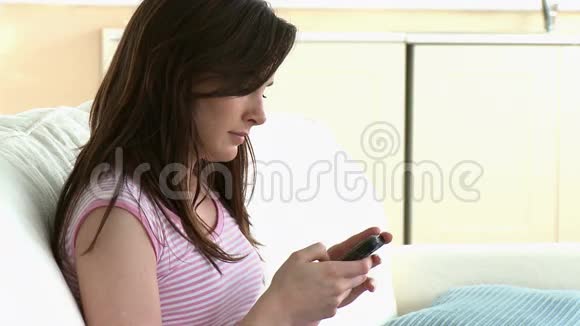 专心致志的女人坐在沙发上发短信视频的预览图