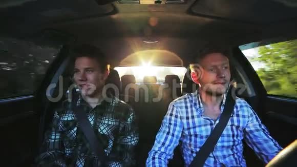 阳光明媚的一天两个滑稽的男人在车里开得很快视频的预览图