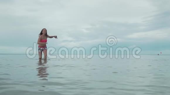 快乐快乐的年轻女孩在水上奔跑浪花慢动作股票录像视频的预览图