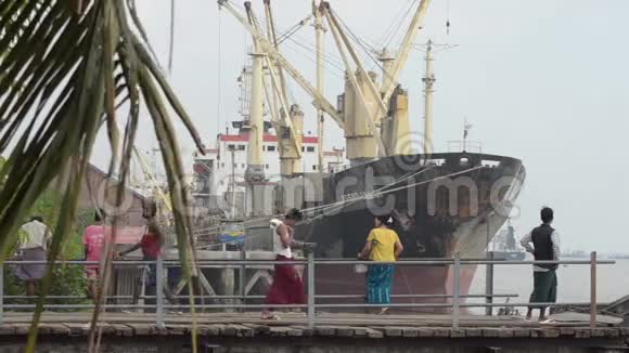港口码头和JTY亚洲搬运工在靠近船只的舷梯上搬运麻袋视频的预览图