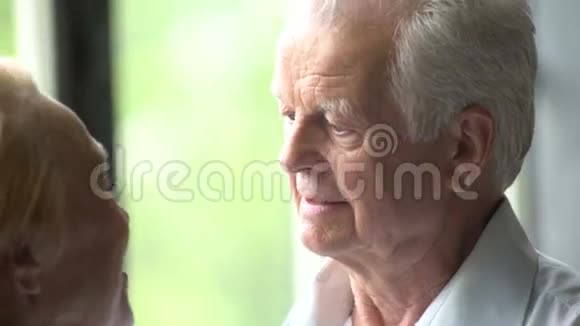 可爱快乐的老年夫妇在现代公寓他们互相交谈微笑拥抱和亲吻视频的预览图