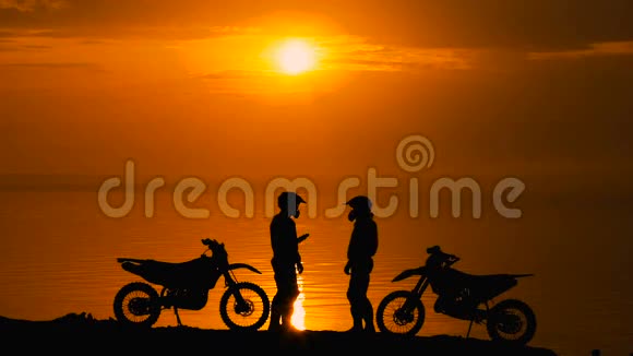 日落时分另外两个摩托车手在北罗古河相遇他们很高兴见到对方并打招呼反对剪影视频的预览图