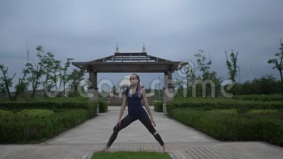年轻的白种人穿着运动服光着脚在城市公园练习瑜伽放松日出背景慢慢视频的预览图