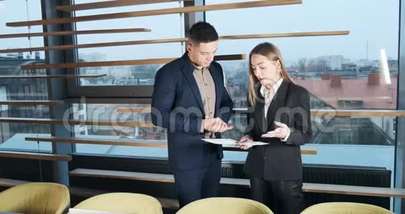男人和女人在灯火通明的现代办公室里讨论工作从事图表文件工作的有关男女视频的预览图