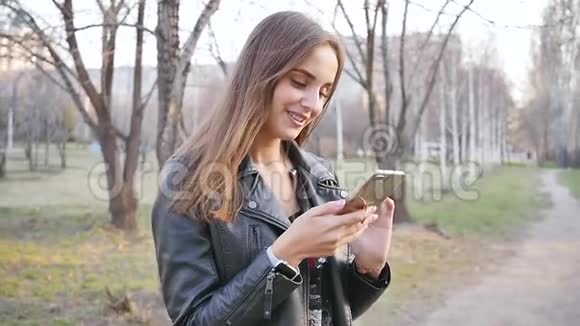 公园里漂亮的年轻女人用电话晚上穿过市中心一个年轻的女人走在视频的预览图
