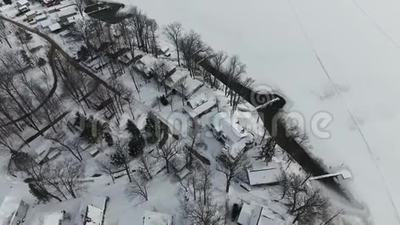 在冰雪覆盖的房屋上飞翔在冰冻的湖滨视频的预览图