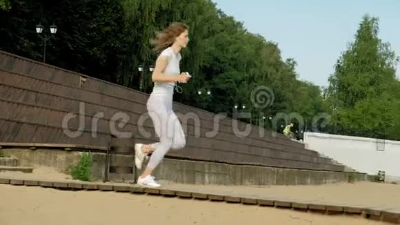 年轻的健身妇女从事户外运动戴着耳机超级慢动作视频的预览图