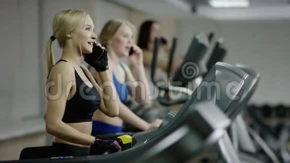 在跑步机上行走的女人在打电话视频的预览图